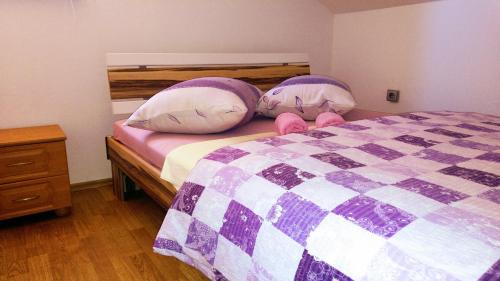 a bedroom with a purple and white bed with two pillows at Apartman Dadić in Malinska