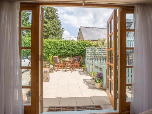 an open door to a patio with a table and chairs at Teagles Cottage in Stow on the Wold