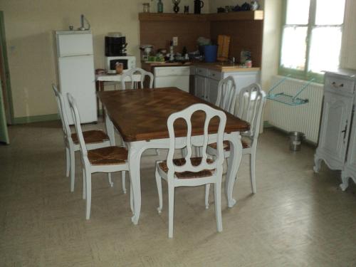 - une cuisine avec une table en bois et des chaises blanches dans l'établissement Appartement, à Villemoisan