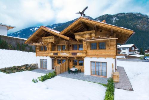 a log house in the snow with mountains in the background at Alpenchalet Brücke in Mayrhofen