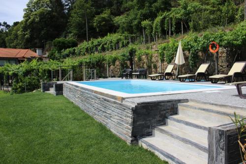 a swimming pool in a yard with chairs and a table at Casa do Escoivo in Loivos da Ribeira