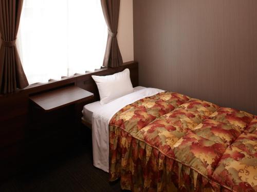 a bed in a hotel room with a window at Osaka Academia in Osaka