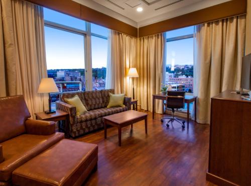a living room with a couch and a desk and windows at Hotel Ithaca in Ithaca