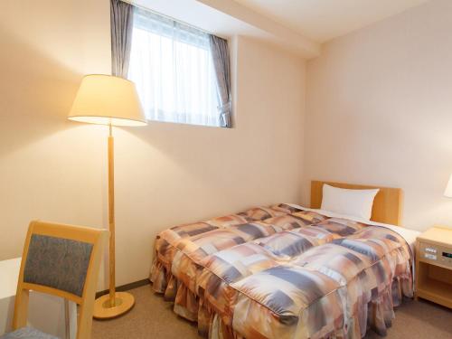 a bedroom with a bed and a lamp and a window at Osaka Academia in Osaka
