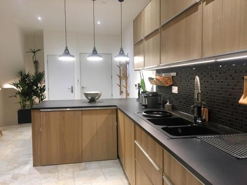 une cuisine avec des armoires en bois et un comptoir noir dans l'établissement Loft Christina moderne et confortable, vue lac, climatisation, parking, à Aix-les-Bains