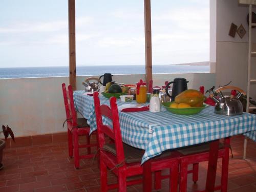 a table with red chairs and a table with food on it at Edificio Magico in Tarrafal