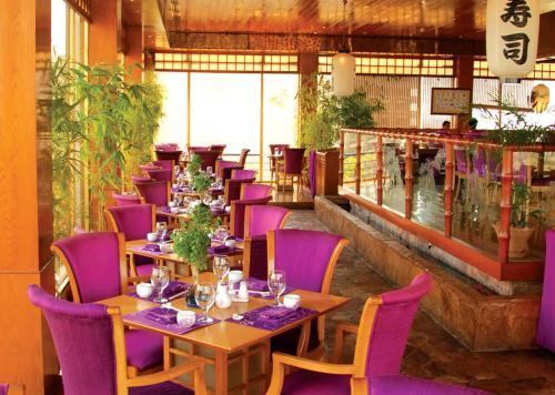 a restaurant with purple chairs and tables in a room at Pearl Continental Hotel, Karachi in Karachi