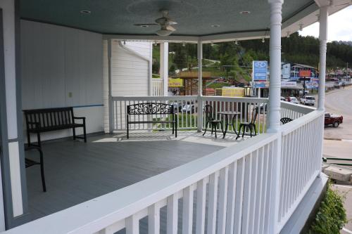 a porch with two chairs and a table at Roosevelt Inn Mount Rushmore in Keystone