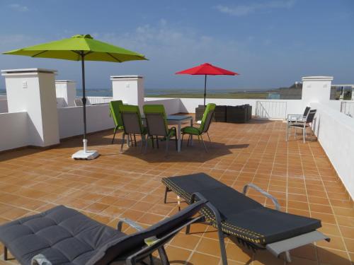 a patio with chairs and tables and umbrellas on a roof at Formosa Village in Fuzeta