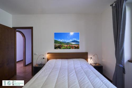 ペルレードにあるCasa Violettaの白い大型ベッドが備わるベッドルーム1室、壁に絵画が飾られています。