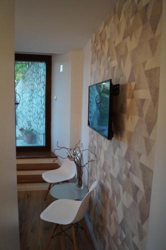 2 sillas blancas, mesa y TV en la pared en Snegar Apartments, en Ohrid