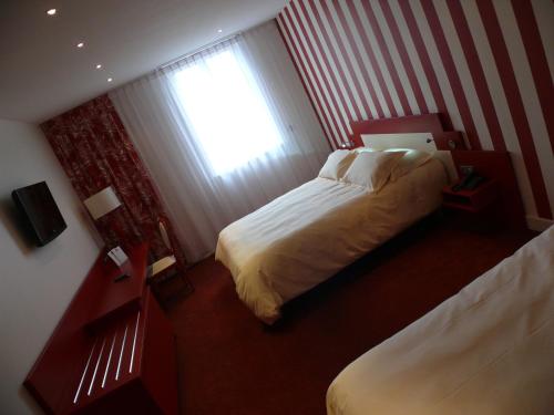 a hotel room with two beds and a window at The Originals Boutique, La Maison Rouge, Lens Ouest in Noeux-les-Mines