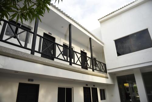 a white building with a balcony with black railing at Hotel El Emigrante in Puerto Colombia