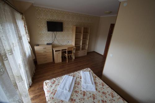 a bedroom with a bed and a desk and a television at Panorama Yasinya in Yasinya