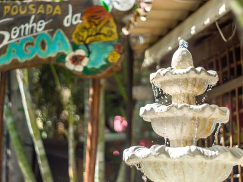 a white fountain in front of a store with a sign at Pousada Sonho da Lagoa in Praia do Forte