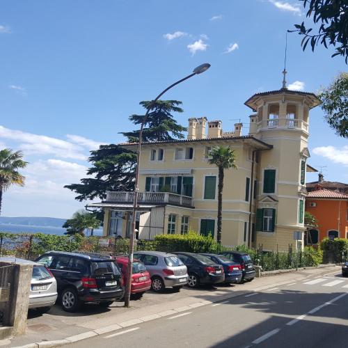 a building with a lot of cars parked in front of it at Apartmani Belsito in Lovran