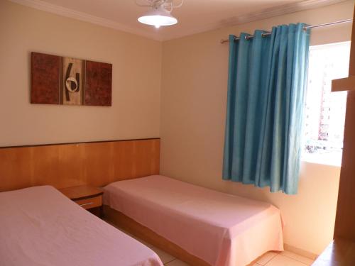 1 dormitorio con 2 camas y cortina azul en Vitória das Thermas - Achei Férias, en Caldas Novas
