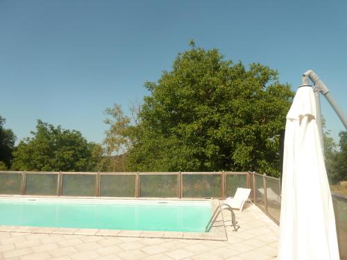 a white umbrella and a chair next to a pool at La Closerie des Arts in Gabillou