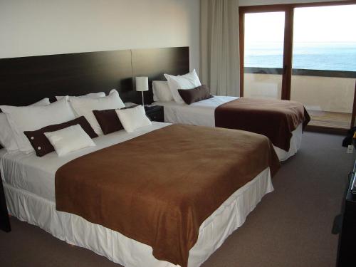 two beds in a hotel room with a large window at View Hotel BRC in San Carlos de Bariloche