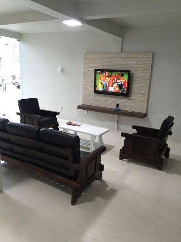 a living room with two chairs and a tv on a wall at Hotel Executivo in São Borja