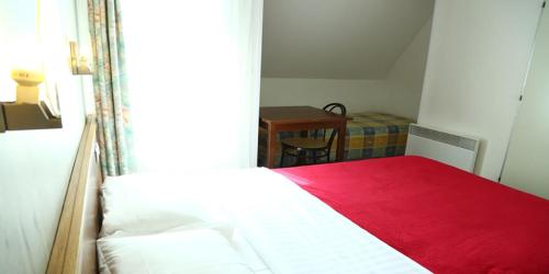 a bedroom with a bed with a red blanket at Hôtel Restaurant Maison Blanche in Rungis