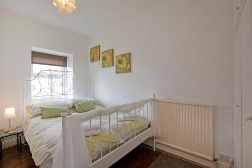 een witte slaapkamer met een bed en twee foto's aan de muur bij Commerce Cottage in Harrogate