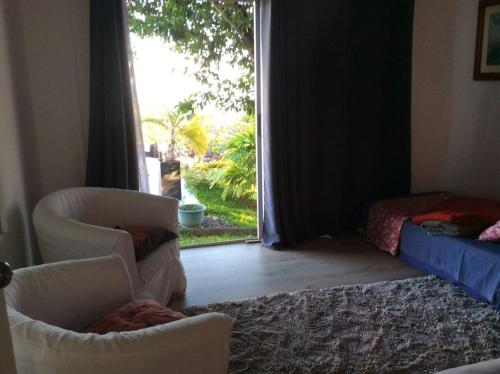 a living room with two chairs and a window at Bungalow Premium Tahiti in Punaauia