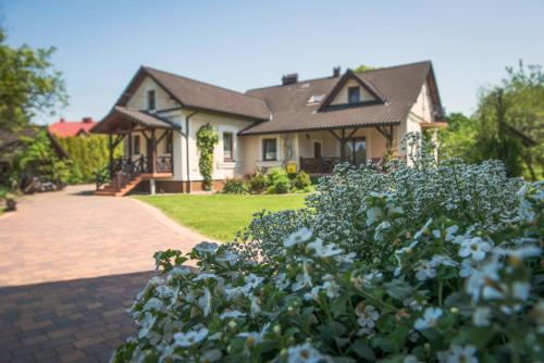 a house with a garden of flowers in front of it at Dworek Galicyjski in Skidzin