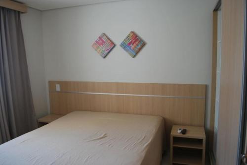 1 dormitorio con 1 cama y 2 cuadros en la pared en Casa da Madeira - Achei Ferias, en Caldas Novas