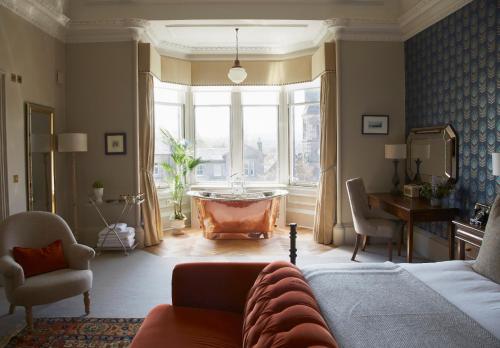 una sala de estar con una cama y una bañera en una ventana en The Roseate Edinburgh - Small Luxury Hotels of the World, en Edimburgo