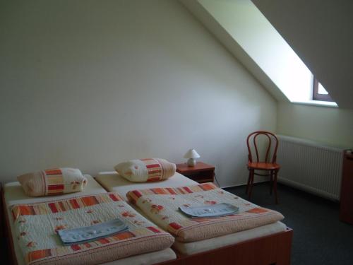 a bedroom with two beds and a chair and a window at Restaurace a Penzion Česká Hospoda in Heřmanice