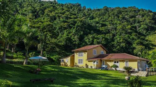 uma casa amarela em frente a uma montanha em Hotel Fazenda Monteiro em Conservatória