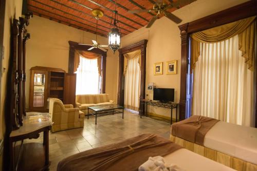 Un dormitorio con dos camas y una sala de estar. en El Gran Hotel, en Mérida