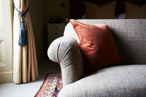 a couch with a red pillow on it next to a window at The Roseate Edinburgh - Small Luxury Hotels of the World in Edinburgh
