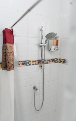 a shower with a hose in a white tiled bathroom at The Lush in Willemstad