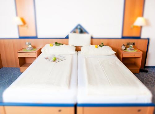 two beds in a hotel room with two tables at Hotel Restaurant Osterbauer in Neunkirchen
