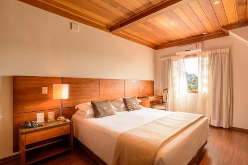 a bedroom with a large bed and a window at Hotel Le Renard - Campos do Jordao in Campos do Jordão