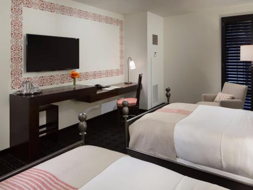 a hotel room with two beds and a desk with a television at Hotel Valencia Riverwalk in San Antonio