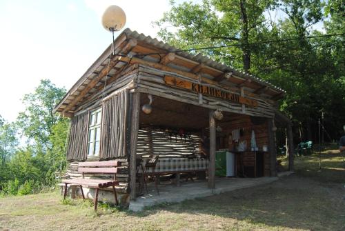 a small wooden building with a bench in the grass at Etno selo Stanojevic in Boljevac