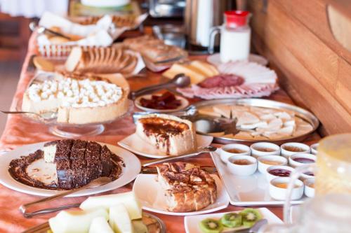 een tafel met veel verschillende soorten voedsel bij Pousada Oliveri in Monte Verde