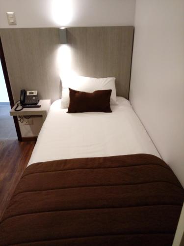 a bedroom with a bed with a pillow and a phone at Hotel Elisa Cole in Santiago
