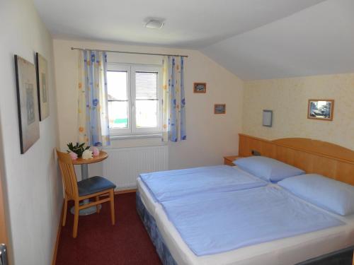 ein Schlafzimmer mit einem Bett, einem Stuhl und einem Fenster in der Unterkunft Landhaus Gassner in Bruck an der Großglocknerstraße