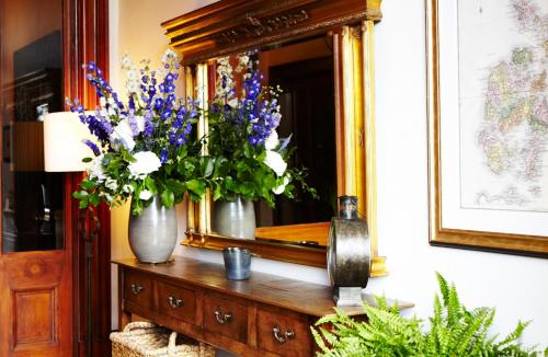 a vase of flowers on a dresser in front of a mirror at The Roseate Edinburgh - Small Luxury Hotels of the World in Edinburgh