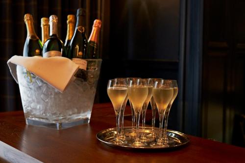 a group of wine glasses on a table with a bucket of champagne at The Roseate Edinburgh - Small Luxury Hotels of the World in Edinburgh