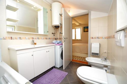 a white bathroom with a sink and a toilet at Apartments Andreja in Kožino