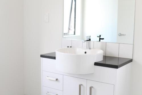 a white bathroom with a sink and a mirror at Uni Motel in Hamilton