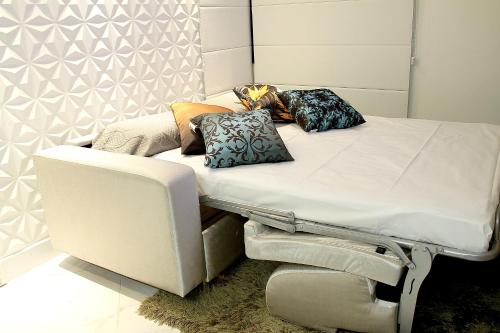 una cama blanca con almohadas junto a una silla en Alameda Lorena Apartment, en São Paulo