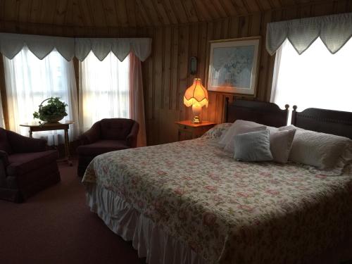 a bedroom with a bed and a lamp and two windows at The Holiday House Inn & Motel in Scarborough