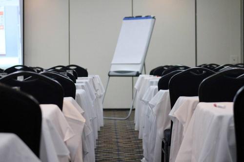 a room with white tables and chairs and a whiteboard at W&P Santo Domingo in Santo Domingo