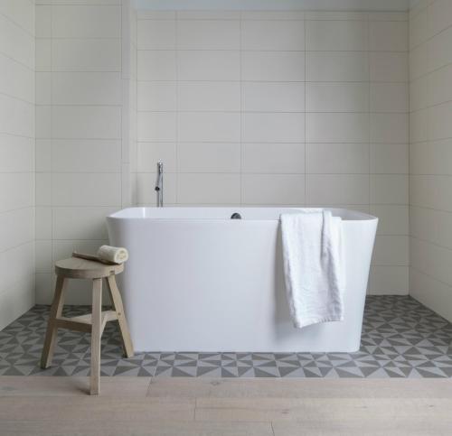 a white bath tub in a bathroom with a stool at Boro Hotel in Queens